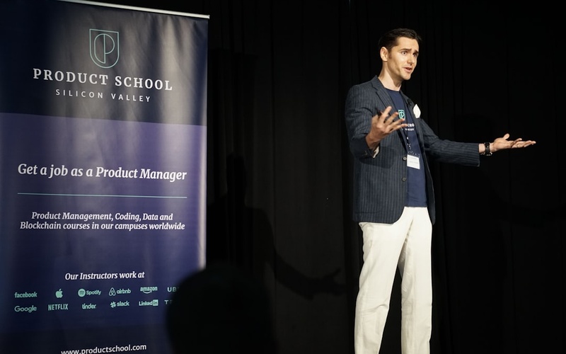 Male student presenting blockchain project to industry mentors in modern conference room